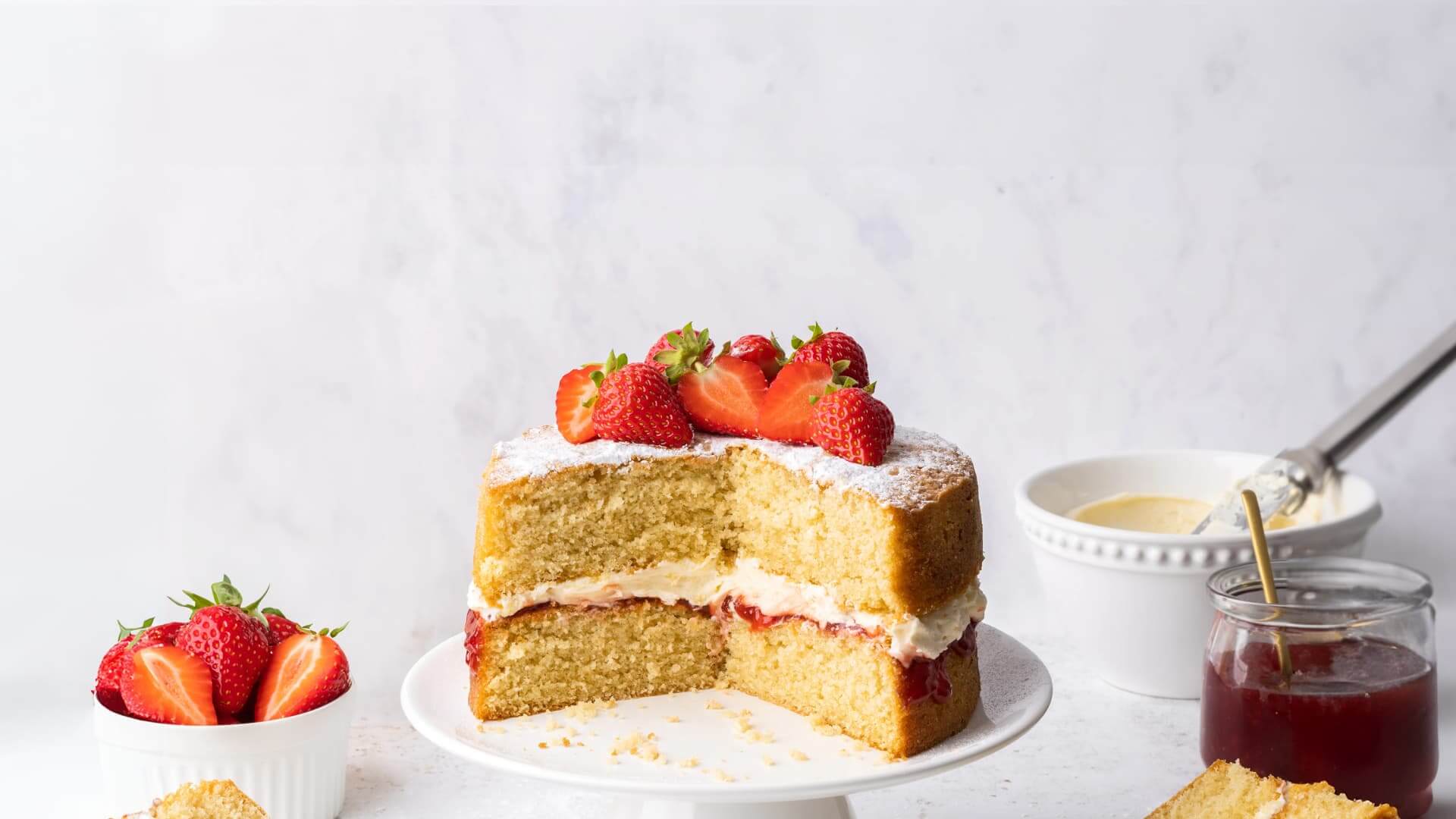 A Victoria Sponge cake with a slice cut from it.